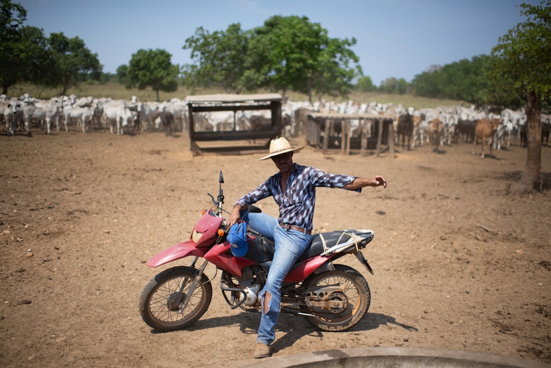 Manager Edvan Bispo op zijn motorfiets. Dit is de boerderij van Reinaldo Marques Queiroz. Op dit deel van zijn land rust een embargo, maar toch grazen er koeien.