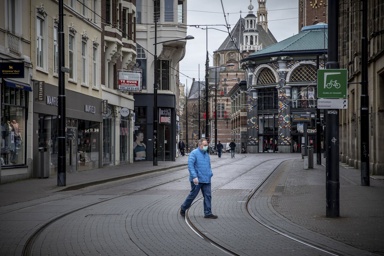 Een man steekt donderdagmiddag een lege winkelstraat over in Den Haag.