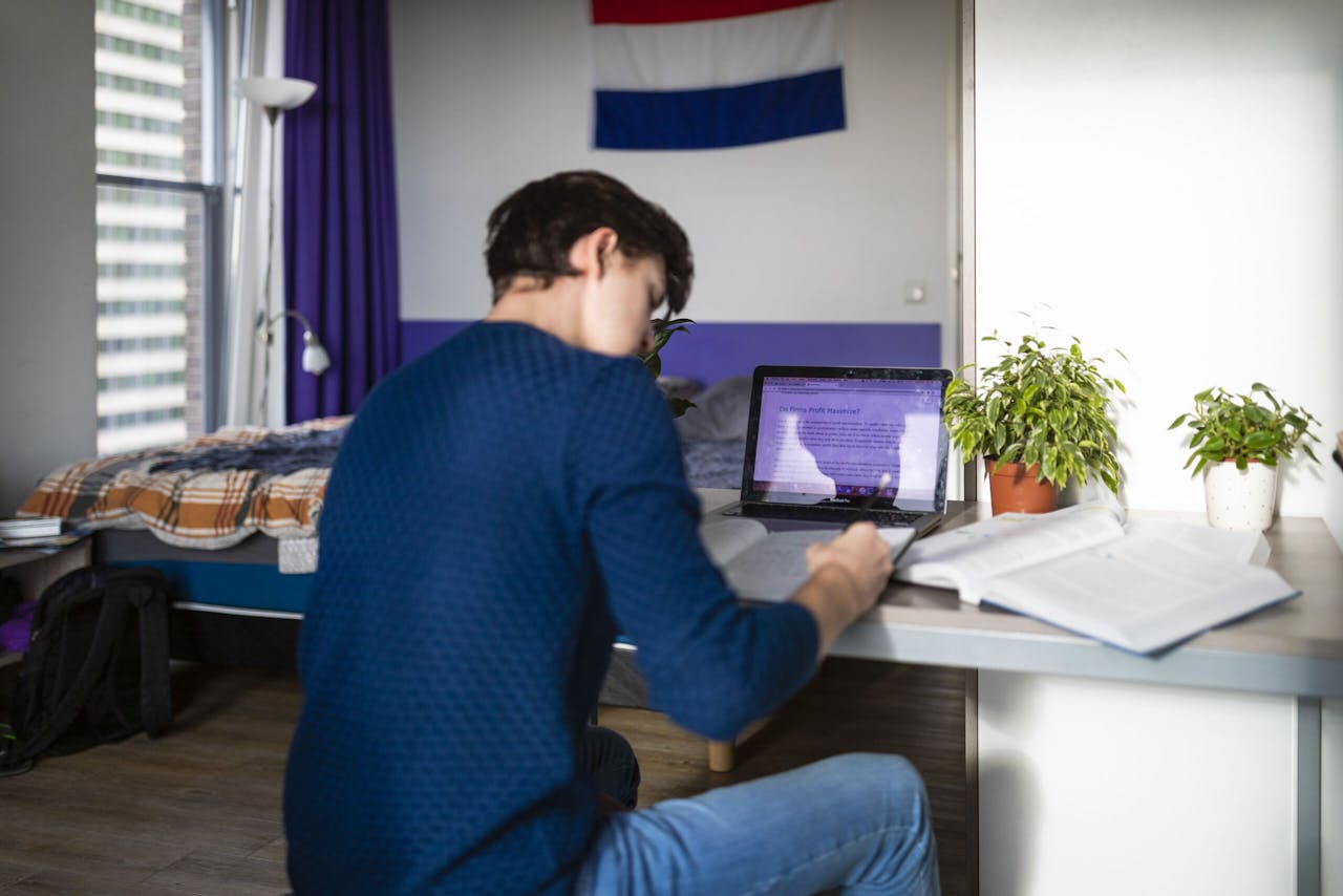 Een student van de Erasmus Universiteit bereidt zich voor op zijn tentamen. Als hij online zijn tentamen moet doen, moet hij achter zich op 1,5 meter de camera van zijn mobieltje installeren om spieken tegen te gaan.