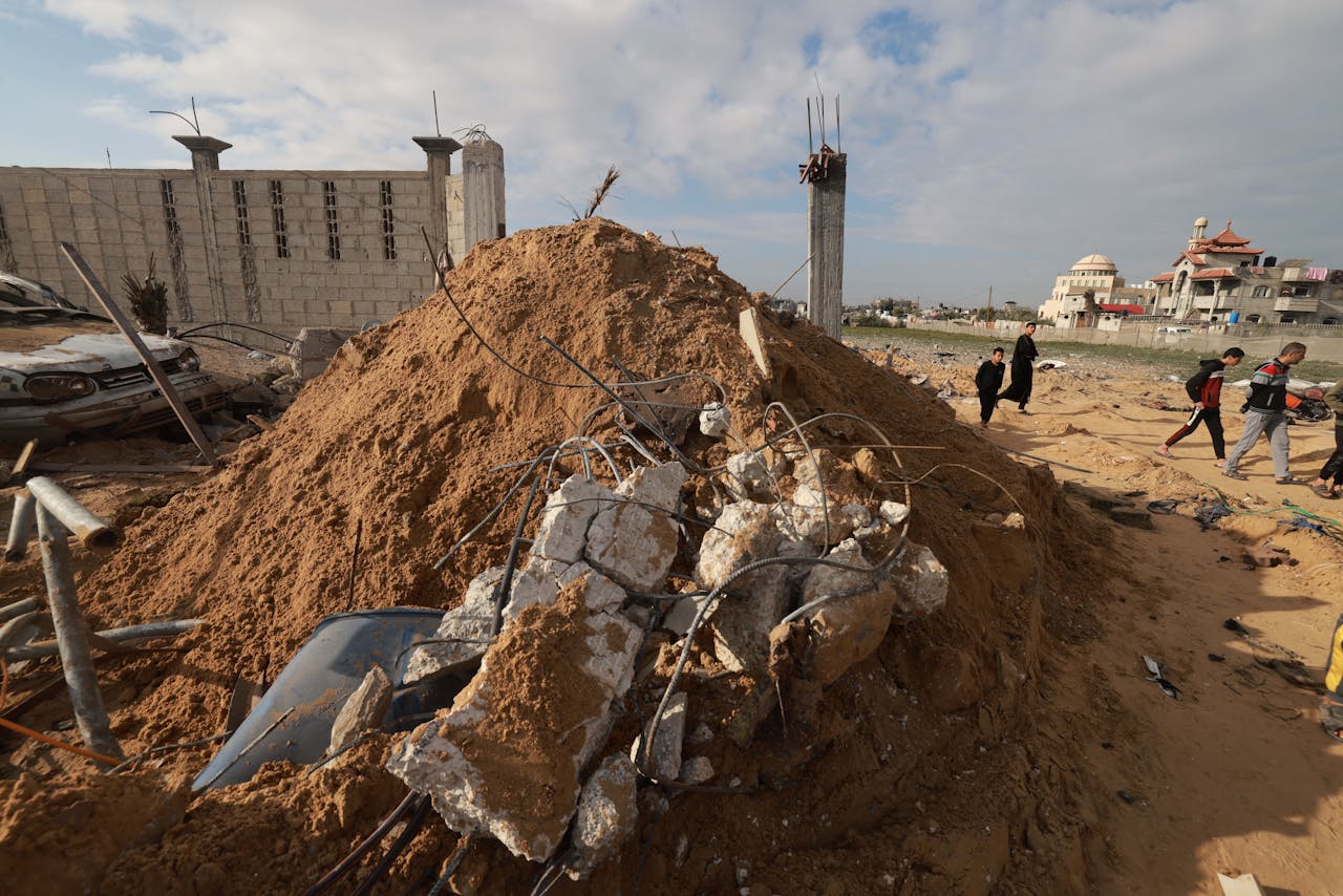 Palestijnen lopen in Rafah langs verwoestingen veroorzaakt door Israëlische luchtaanvallen. Rafah grenst aan Egypte.