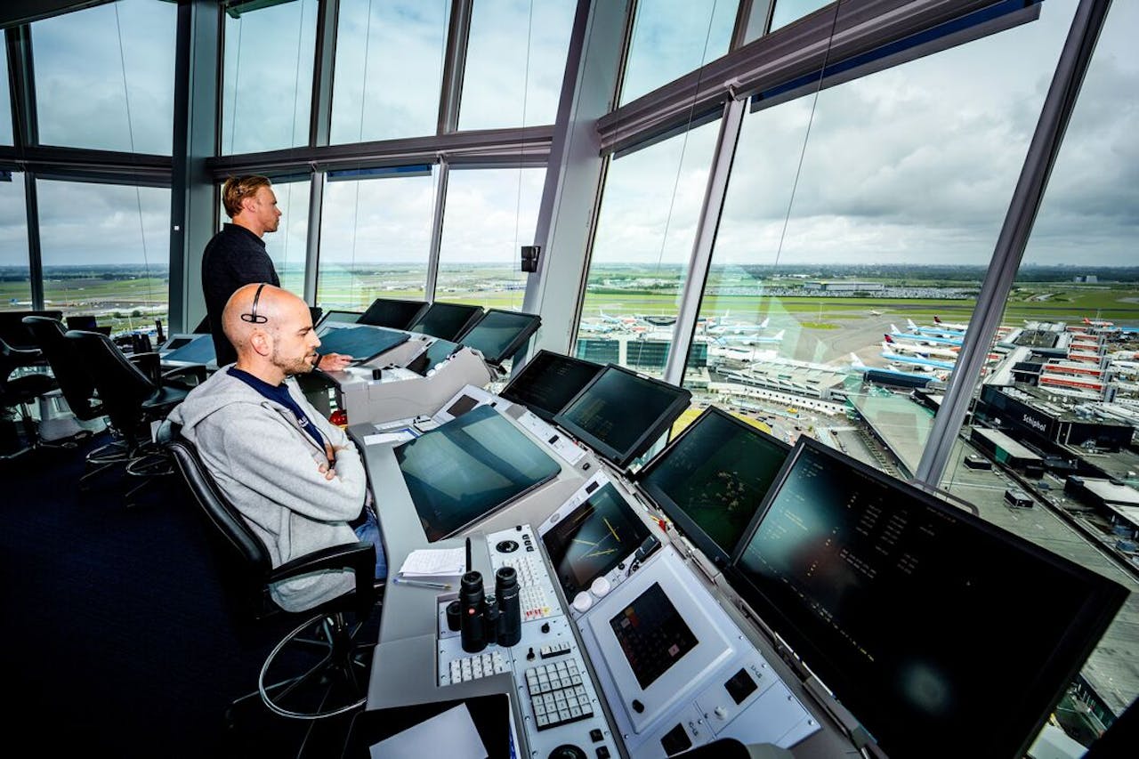 Luchtverkeersleiders aan het werk in de verkeerstoren van Schiphol. De luchtvaartmaatschappijen keren zich tegen een forse verhoging van de havengelden.