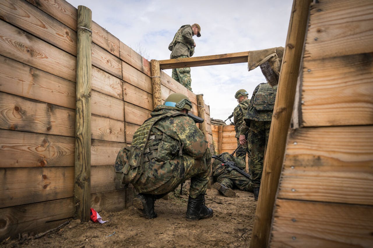 Oekraïense militairen leren in een loopgraaf om in een onoverzichtelijke situatie eerst hun mitrailleur naar voren te brengen.
