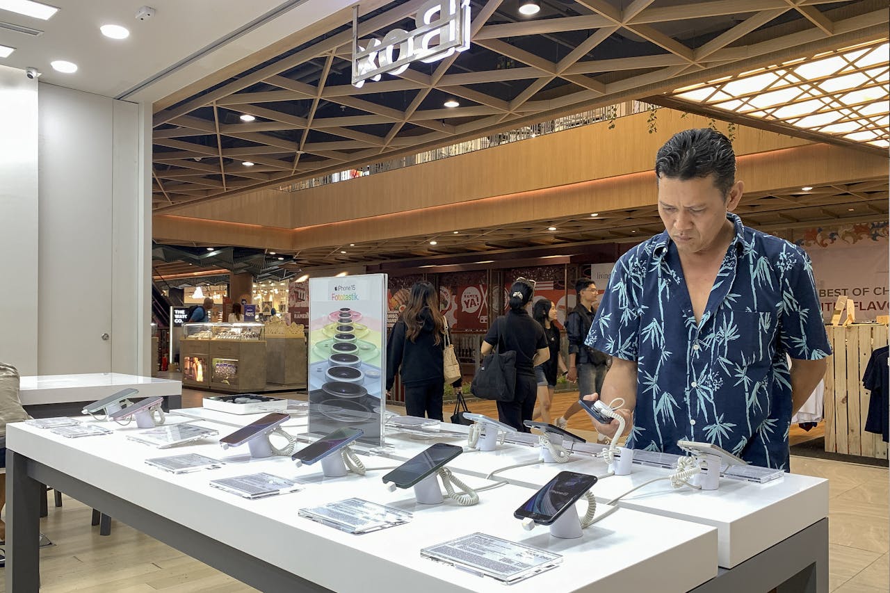 Een klant bekijkt iPhones van Apple in een winkelcentrum in Denpasar op Bali.
