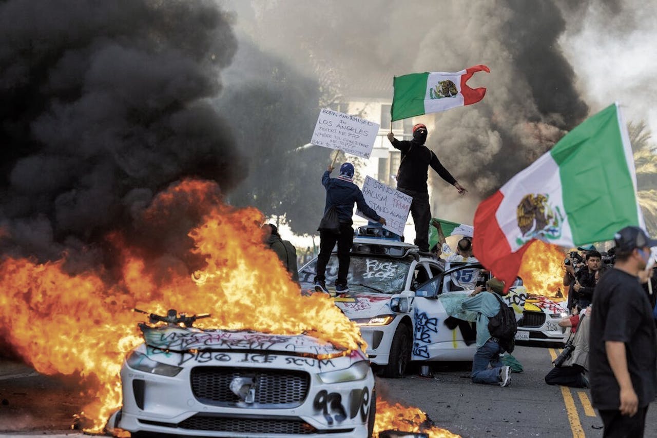 Demonstranten in LA, met brandende taxi’s van Google-dochter Waymo