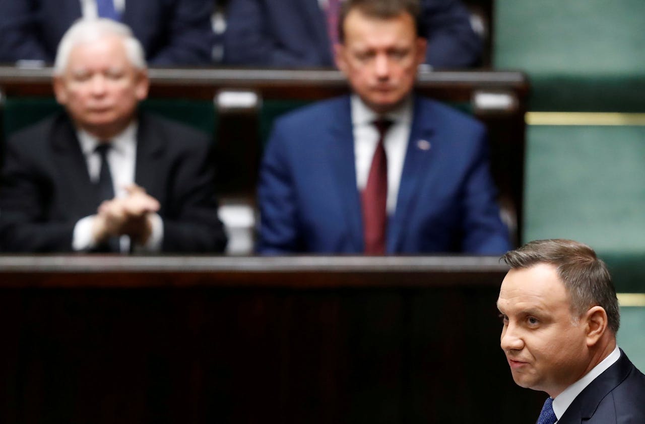 De Poolse president Andrzej Duda spreekt het parlement toe. Op de achtergrond links Jaroslaw Kaczynski, de leider van de regeringspartij PiS waaraan Duda is gelieerd.