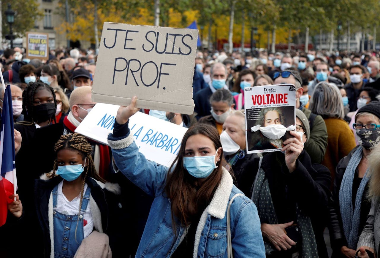 Tijdens een herdenkingsbijeenkomst voor de onthoofde leraar Samuel Paty op Place de la Republique in Parijs, dragen mensen borden met de tekst 'Ik ben leraar'.