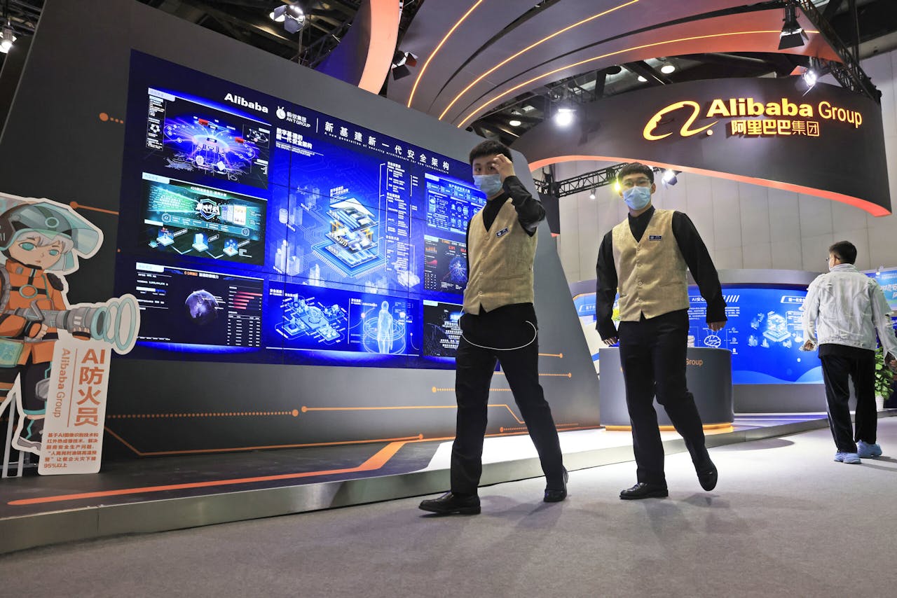 Medewerkers van een techbeurs in Peking wandelen langs een digitale wand van Alibaba. de webwinkelgigant die door Chinese mededingingsautoriteiten onder vuur werd genomen wegens een vermeende monopoliepositie.