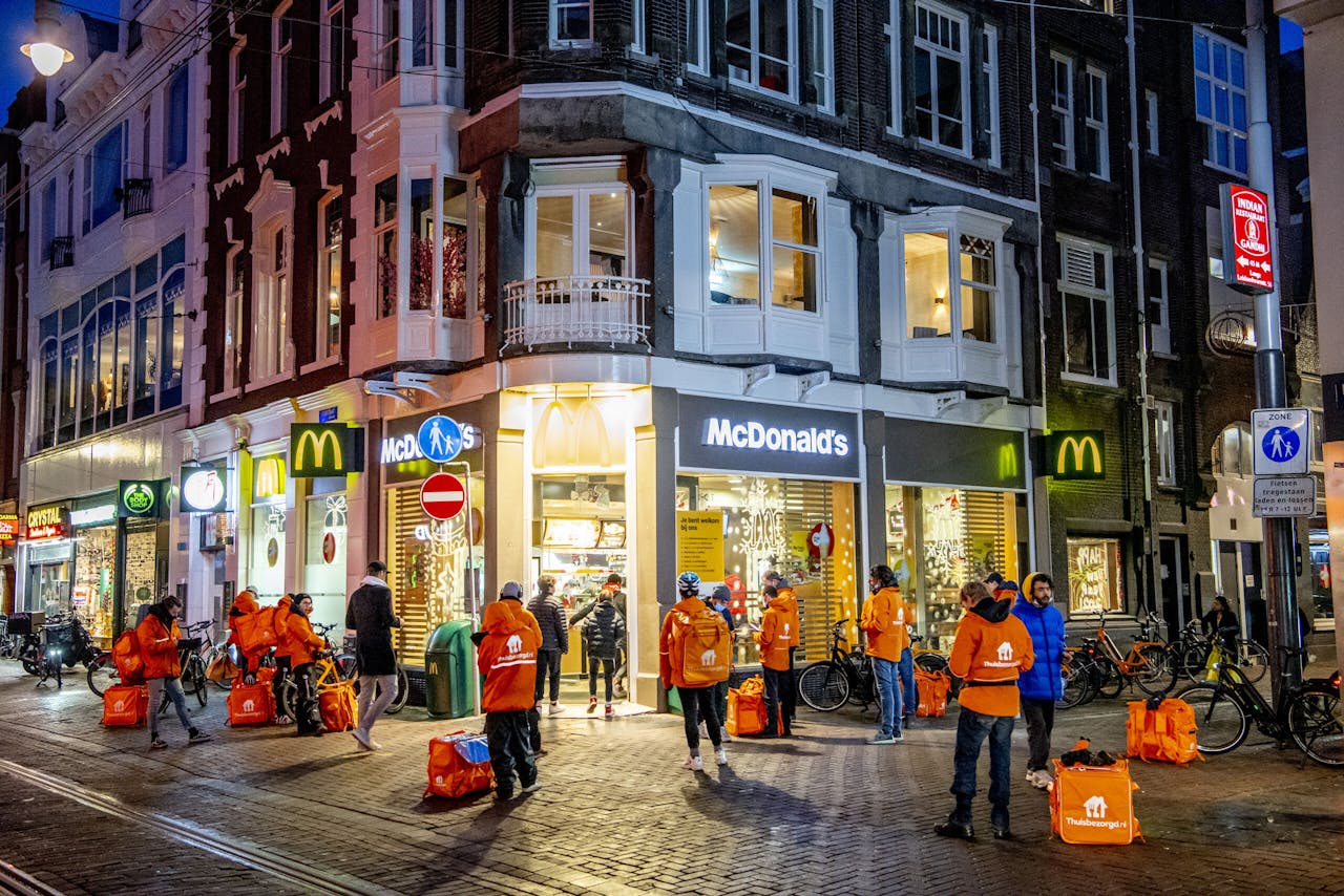 Maaltijdbezorgers van Thuisbezorgd.nl halen bestellingen op bij de McDonald's in de Leidsestraat in Amsterdam.
