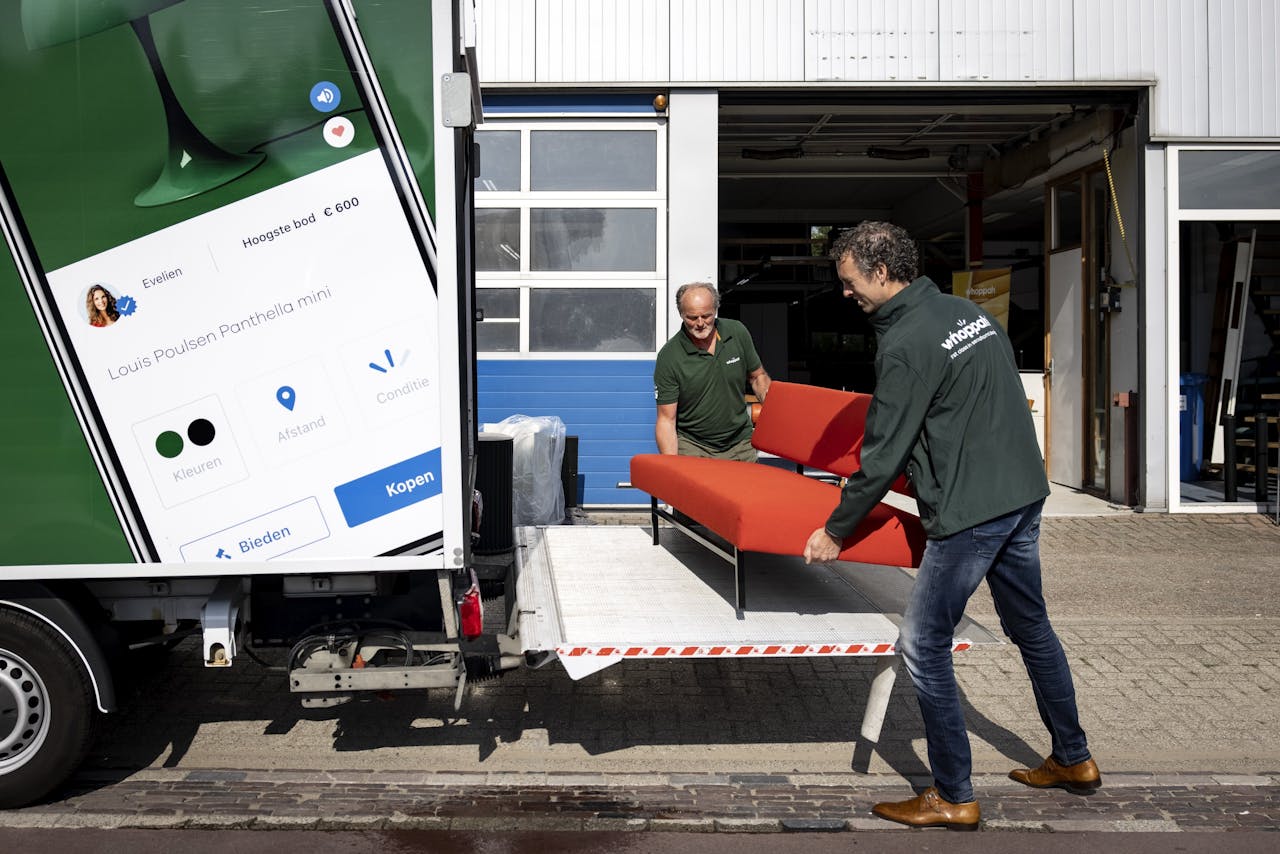 Medewerkers van Whoppah verplaatsen vintage meubilair in een loods van het bedrijf.