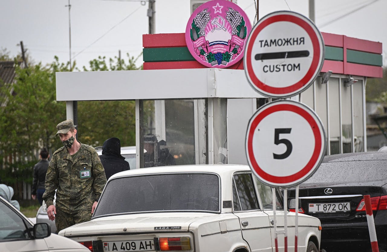 Een soldaat kijkt toe hoe een rij auto's de Moldavische regio binnenrijdt.