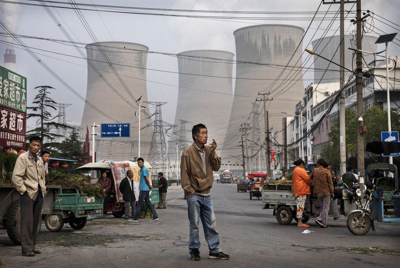 Marktkooplui met een kolencentrale als decor, in Huainan, een grote stad in de oostelijke provincie Anhui in China. Of de Chinese president Xi Jinping naar de klimaattop in Glasgow komt, is onzeker.