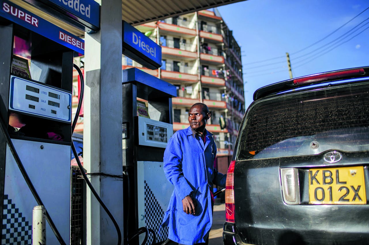 Een pompbediende in de Keniaanse hoofdstad Nairobi gooit een auto vol met diesel.