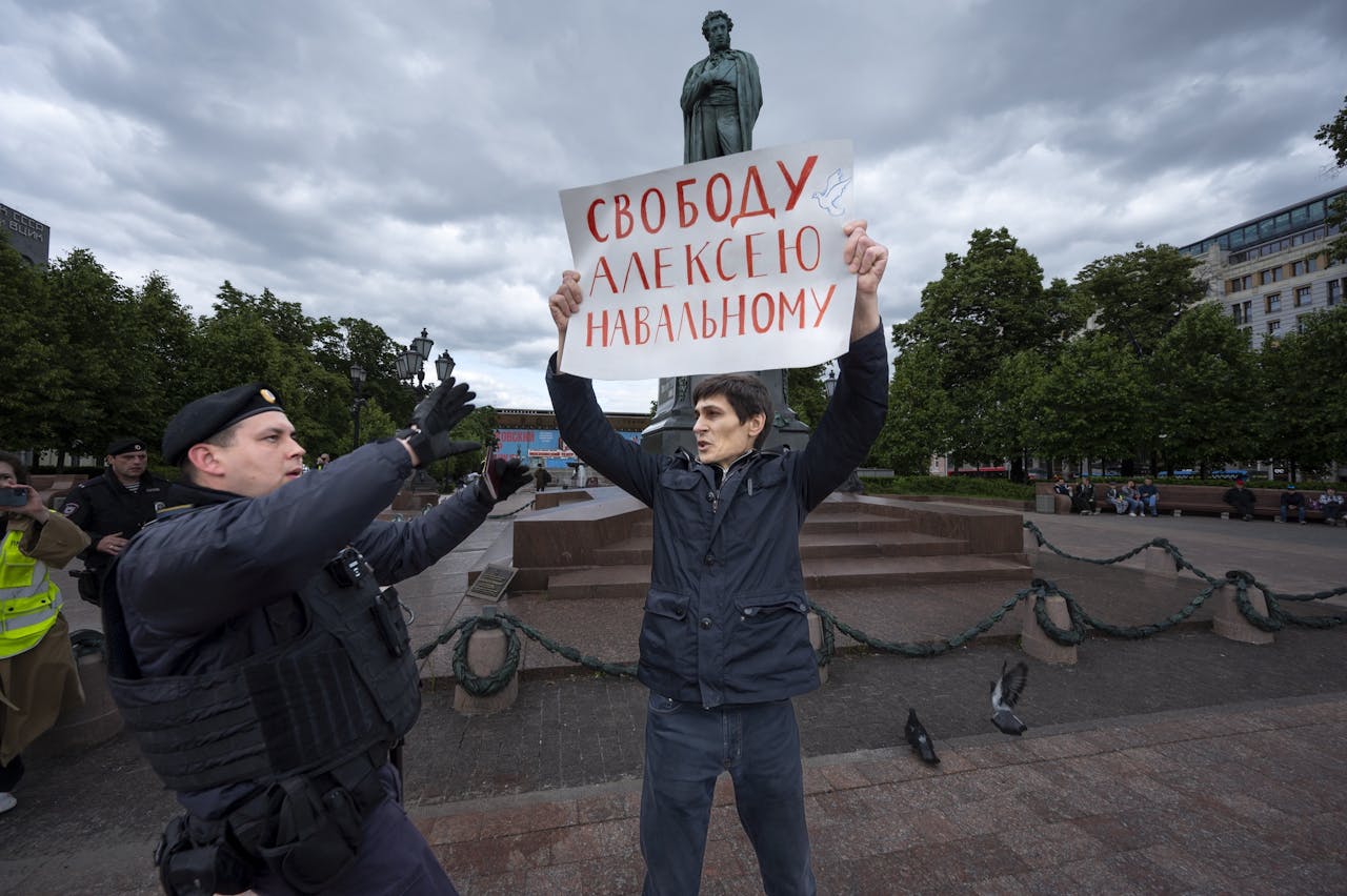Een politieagent arresteert een demonstrant die een bord omhooghoudt met de tekst 'Vrijheid voor Aleksej Navalny', op het Poesjkinplein in Moskou.
