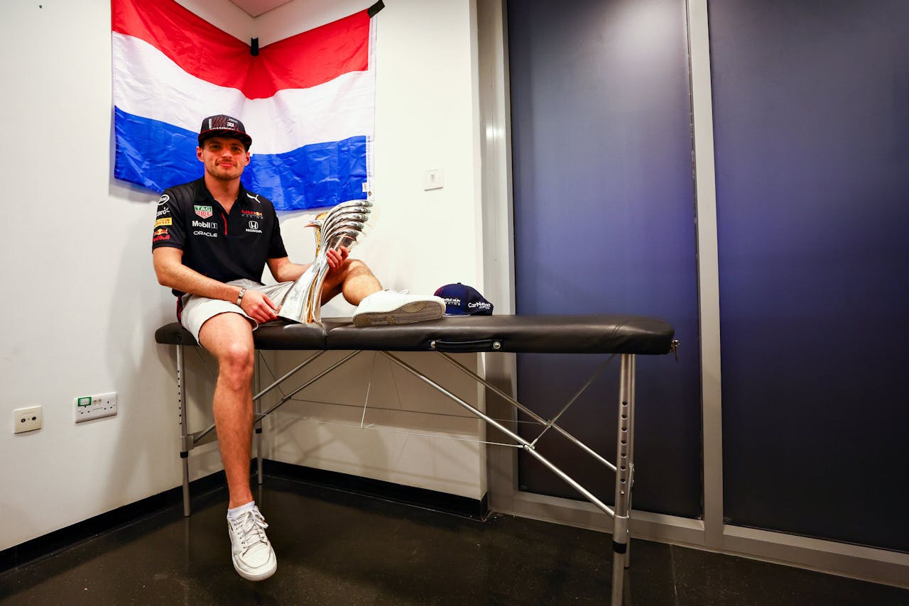 Max Verstappen poseert zittend op de massagebank met zijn net gewonnen prijs na de Grand Prix in Abu Dhabi.
