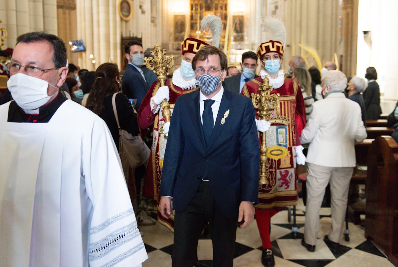 De Madrileense burgemeester José Luis Martínez-Almeida (midden, in blauw pak) is vanwege het Spaanse Sywertschandaal ook in opspraak geraakt. Hij bezocht zondag de mis voor Palmzondag in de kathedraal van La Almudena.