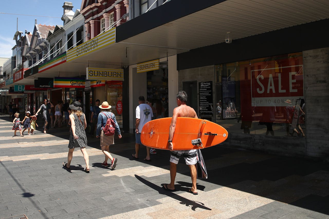Op Manly Beach in Sydney loopt een surfer langs wat winkeltjes.