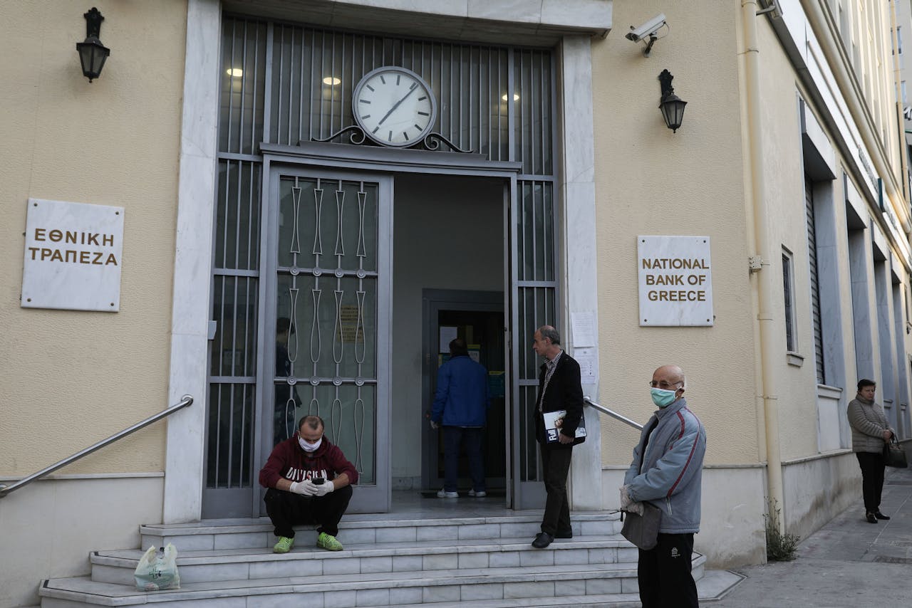 Grieken wachten met mondkapjes op bij een vestiging van de Griekse nationale bank.