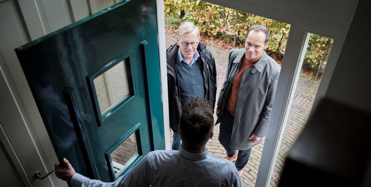 Frank Lentz en Maurits van Laarhoven op bezoek bij een van de bewoners van de Haagse wijk Ypenburg.