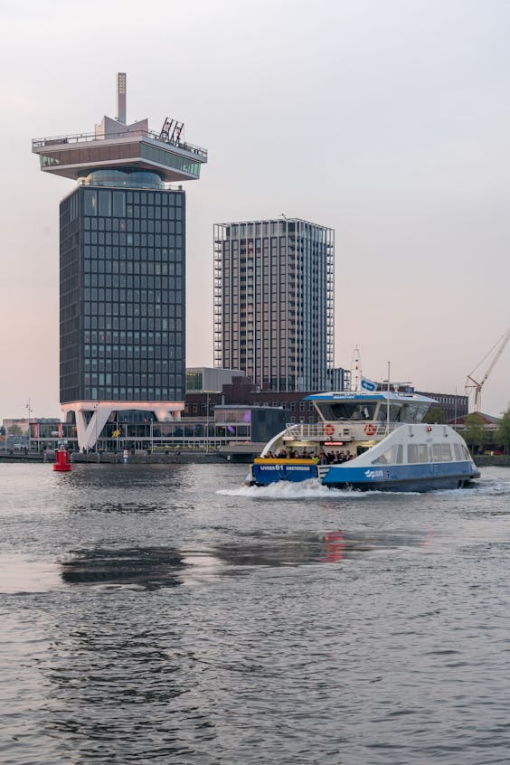 Links de nieuwe woontoren in Amsterdam-Noord, gezien vanaf de andere kant van het IJ.