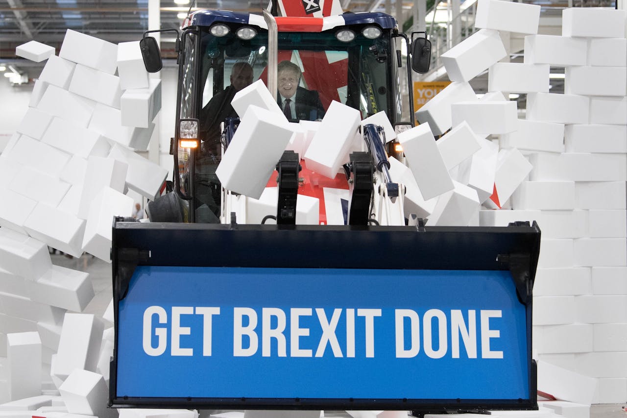Boris Johnson rijdt een graafmachine van de Britse fabrikant JCB door een nepmuur tijdens de campagne voor de Lagerhuisverkiezingen van 12 december 2019.