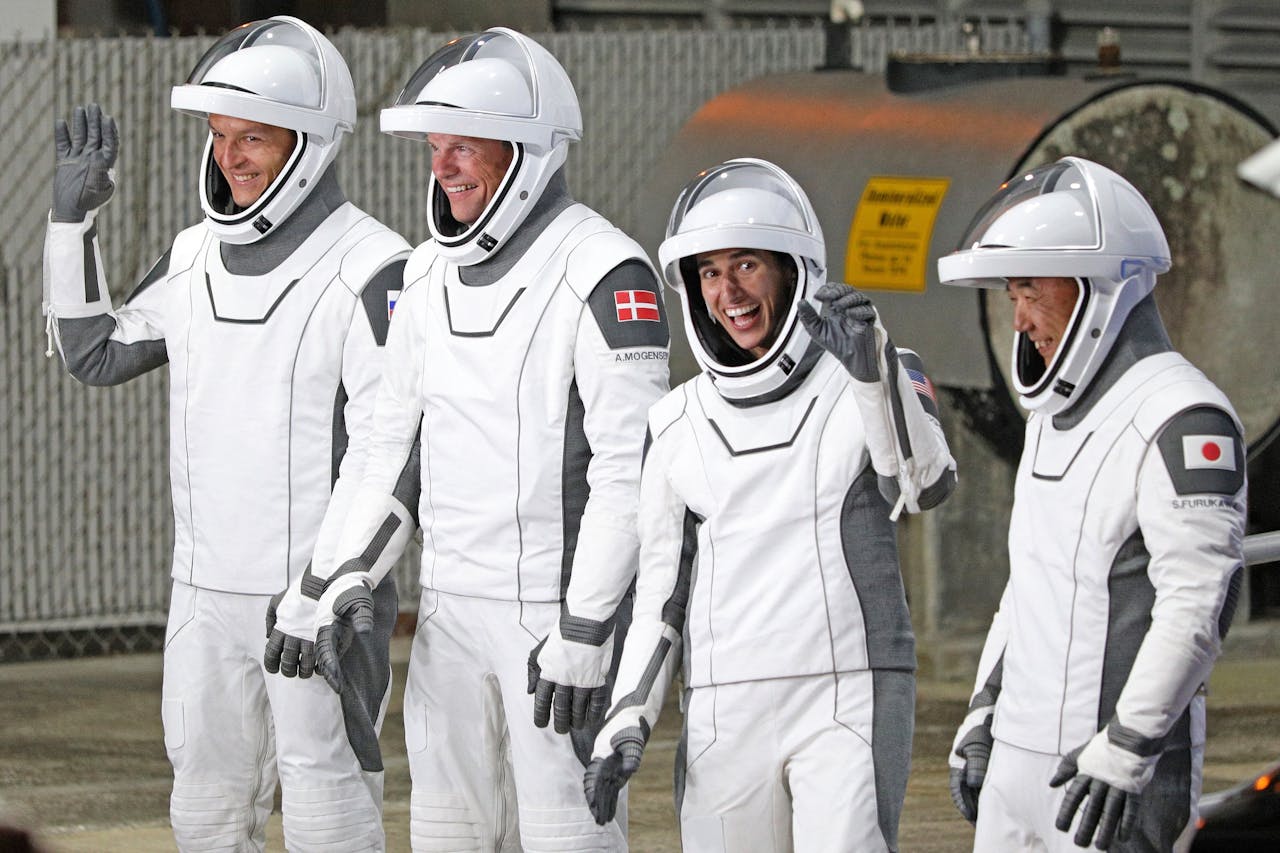 De vier astronauten zwaaien de pers en hun familie uit voordat ze aan boord stappen van de SpaceX Crew Dragon. De Rus Konstantin Borisov (links), de Deen Andreas Mogensen, de Amerikaan Jasmin Moghbeli en Japanner Satoshi Furukawa.
