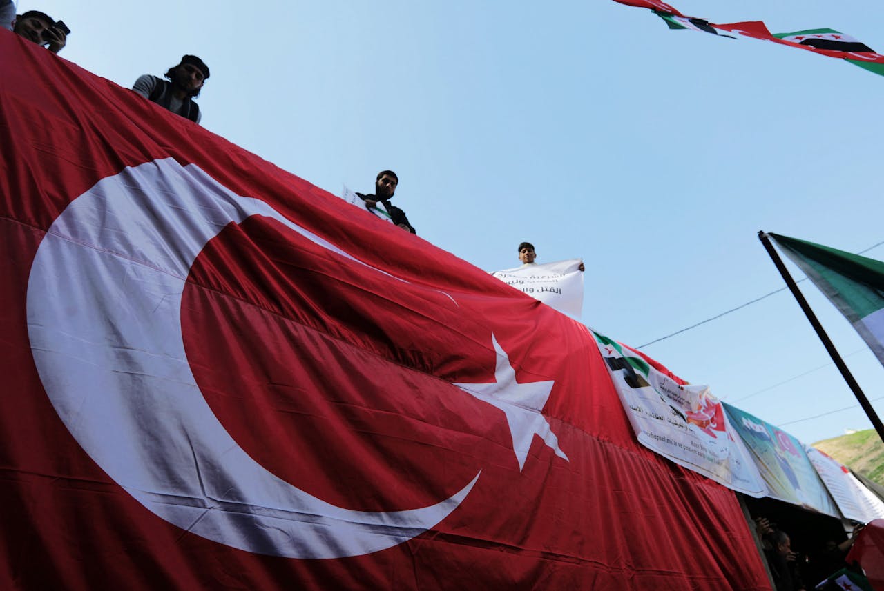 Protestdeelnemers in Azaz, Syriër staan bij een Turkse vlag bij een protest ter ondersteuning van het Tukrse leger en de door Turkije gesteunde Syrische rebellen.