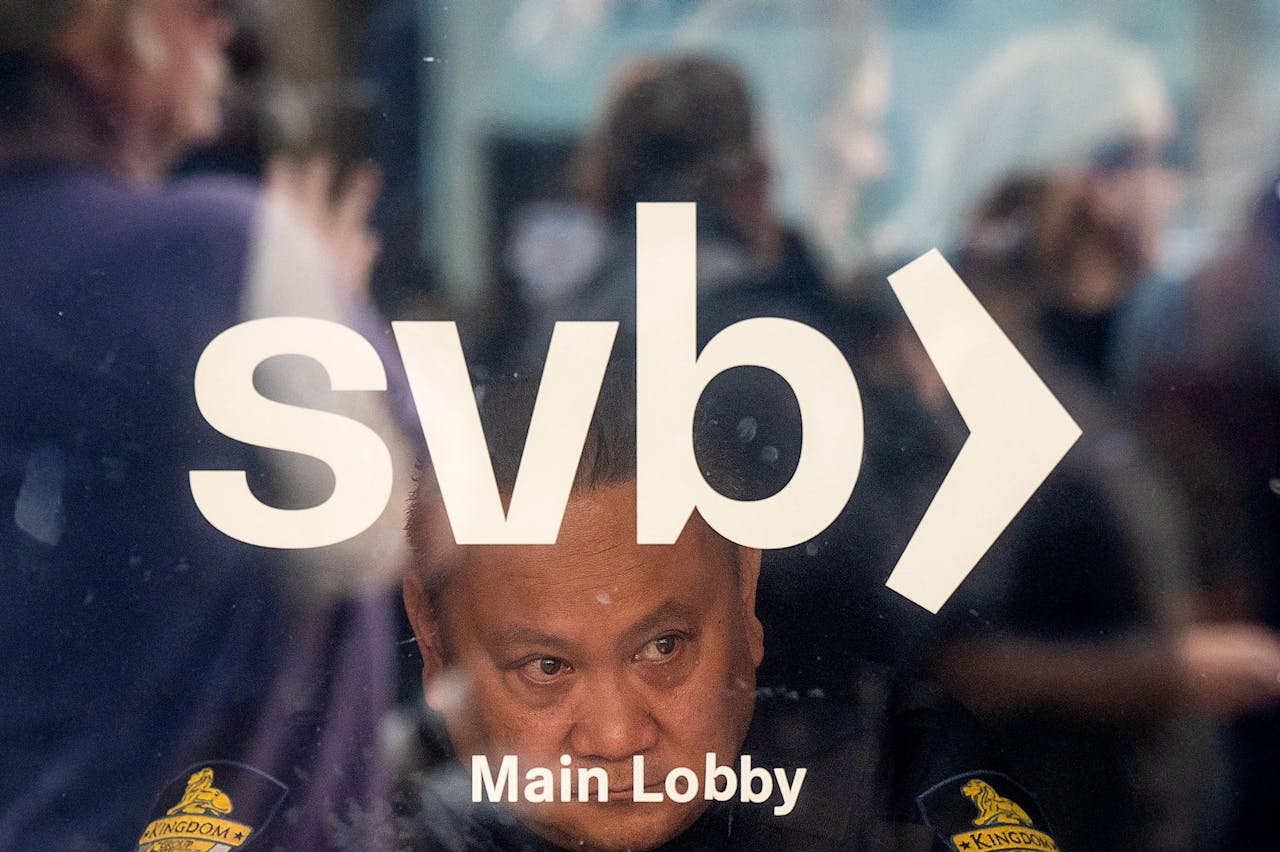 Een beveiliger kijkt uit het raam terwijl zich een rij met klanten vormt voor het hoofdkantoor van Silicon Valley Bank in Santa Clara, Californië.
