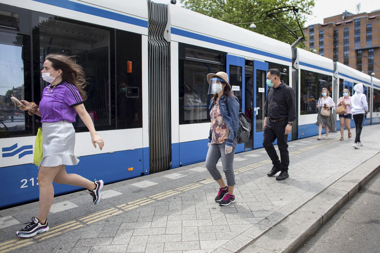 De mondkapjes zijn sinds maandag onderdeel geworden van de vaste reizigers-uitrusting in het openbaar vervoer, zoals hier bij de Amsterdamse tram halte Leidseplein.