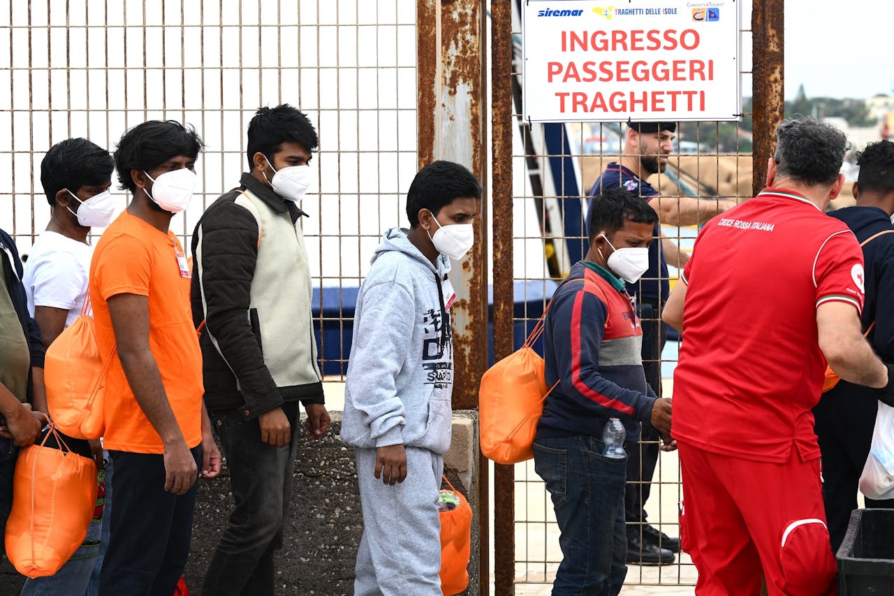 Migranten wachten in de rij voor ze aan boord kunnen van een boot in de haven van het Italiaanse eiland Lampedusa.