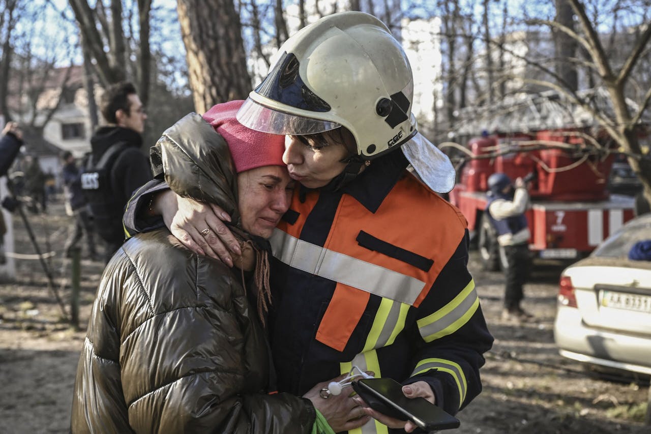 Een reddingswerker troost een geëvacueerde bewoner van een brandende flat in Kiev. De stad is opnieuw doelwit van Russische beschietingen en bombardementen.