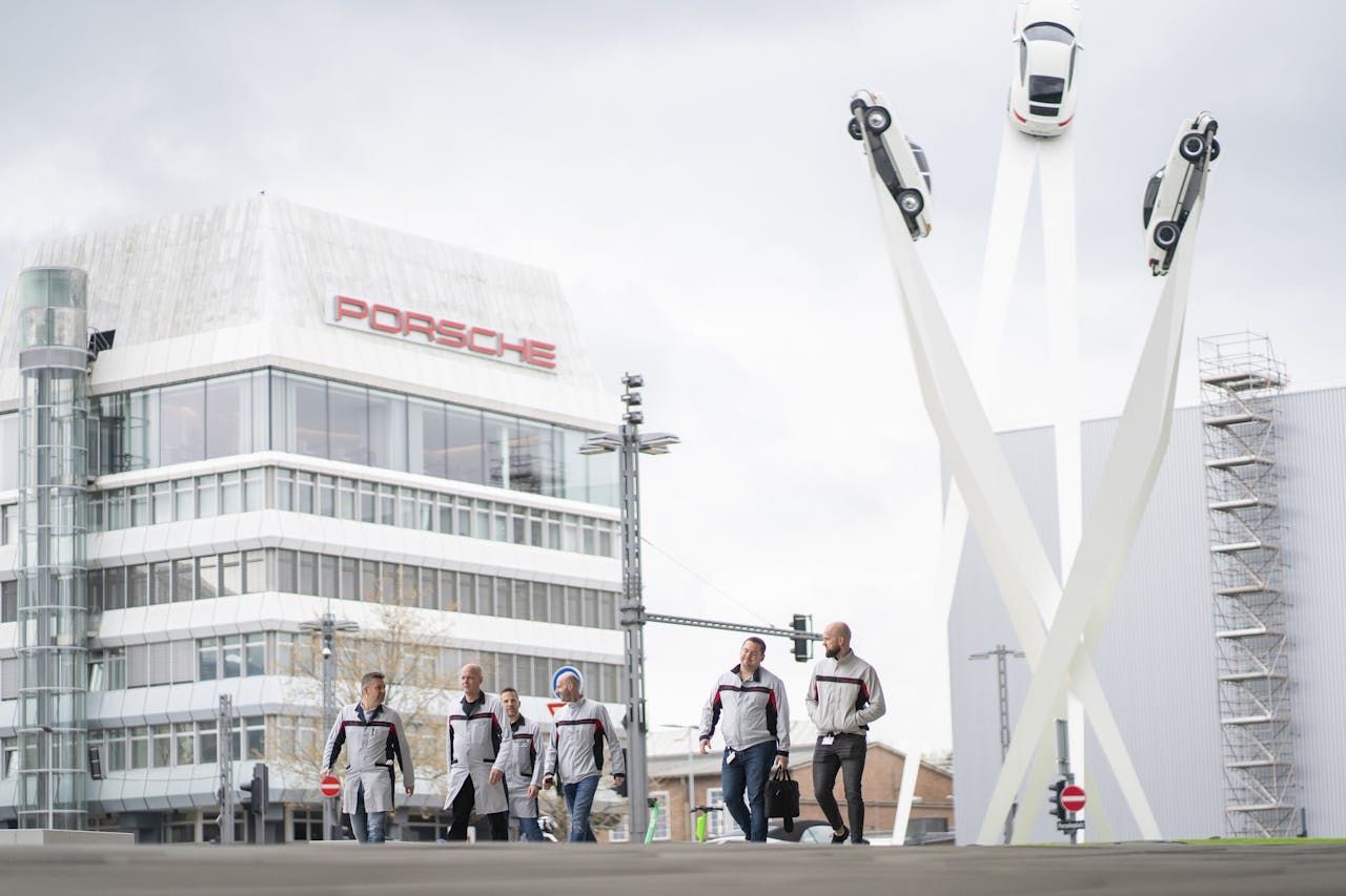 Werknemers van Porsche lopen op het Porscheplatz in Stuttgart langs een een kunstwerk dat de onbegrensde mogelijkheden moet uitstralen. Twee weken na de onthulling in 2015 brak de dieselcrisis uit.
