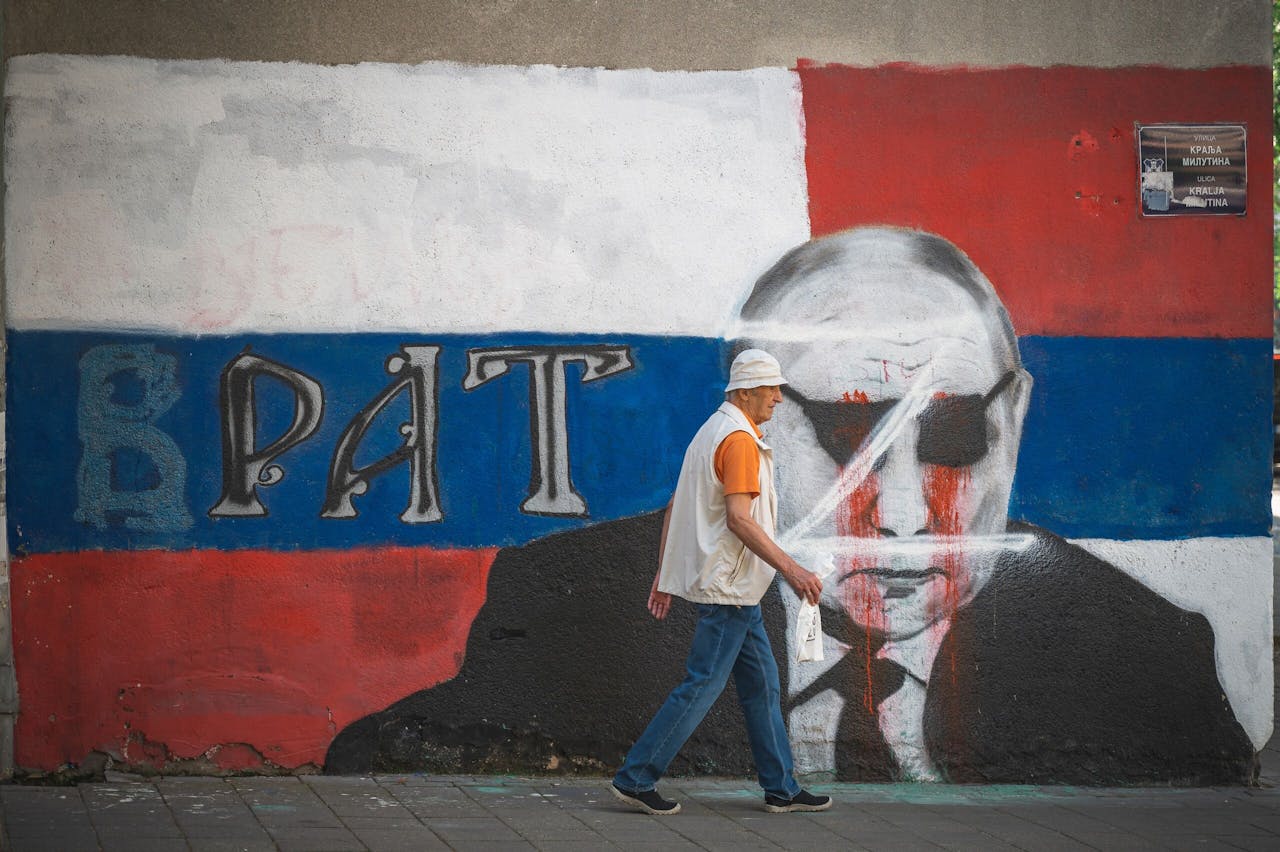 Een voetganger passeert een door critici aangepaste muurschildering van Vladimir Poetin in Belgrado. De b van het woord Brat (broer) is weggepoetst.