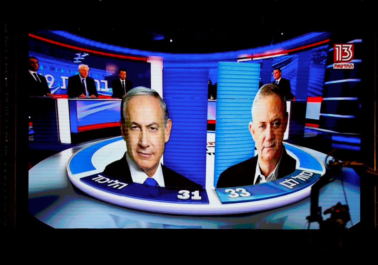 De resultaten van de exitpolls dinsdagavond op een scherm bij Benny Gantz's Blauw-Wit partij. Links Netanyahu, rechts Gantz.