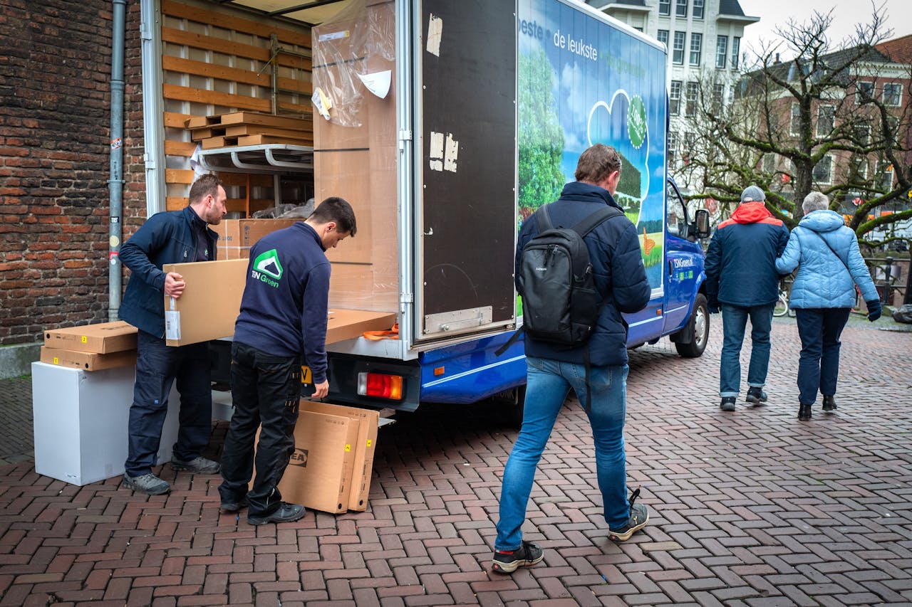 Medewerkers van TSN Groen lossen in de binnenstad van Utrecht dozen van Ikea uit een elektrische vrachtwagen.