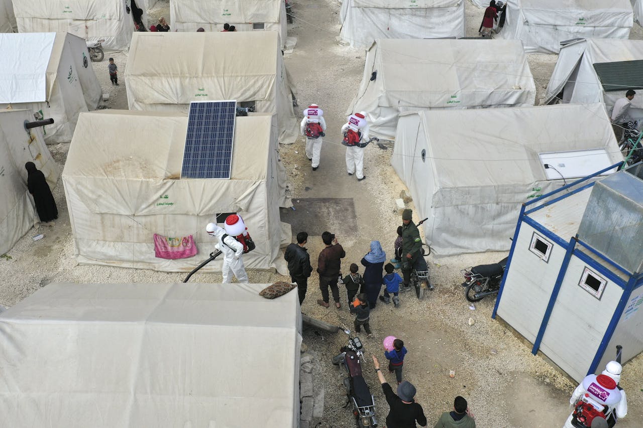 Werkers desinfecteren een vluchtelingenkamp in Idlib. Het coronavirus kan in het Midden-Oosten miljoenen levens in conflictgebieden op het spel zetten, schrijft Het Rode Kruis in een verklaring.