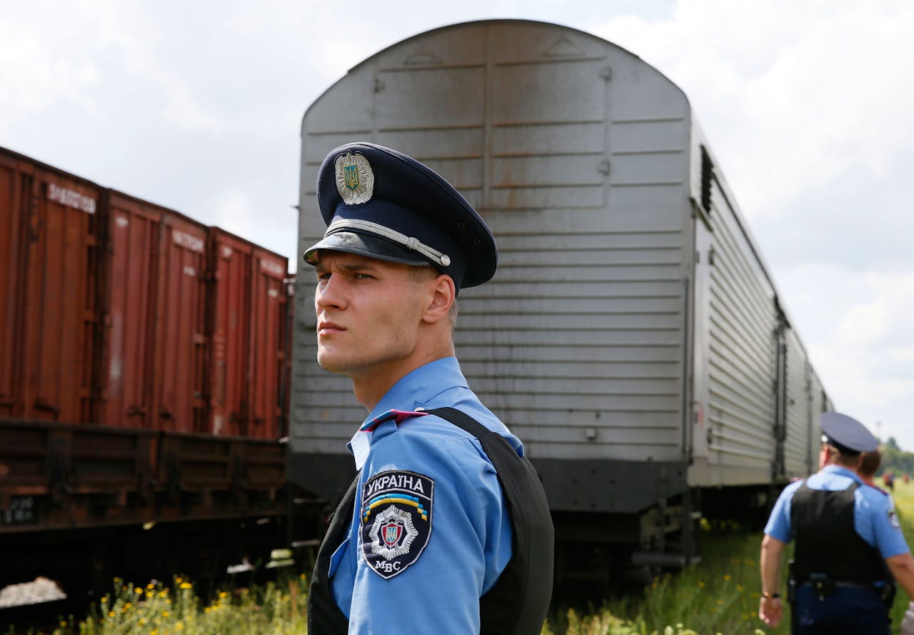 Een Oekraïnse politieagent bewaakt de trein met de lichamen van de overleden passagiers van het vliegtuig van Malaysia Airlines op het station van Charkov.