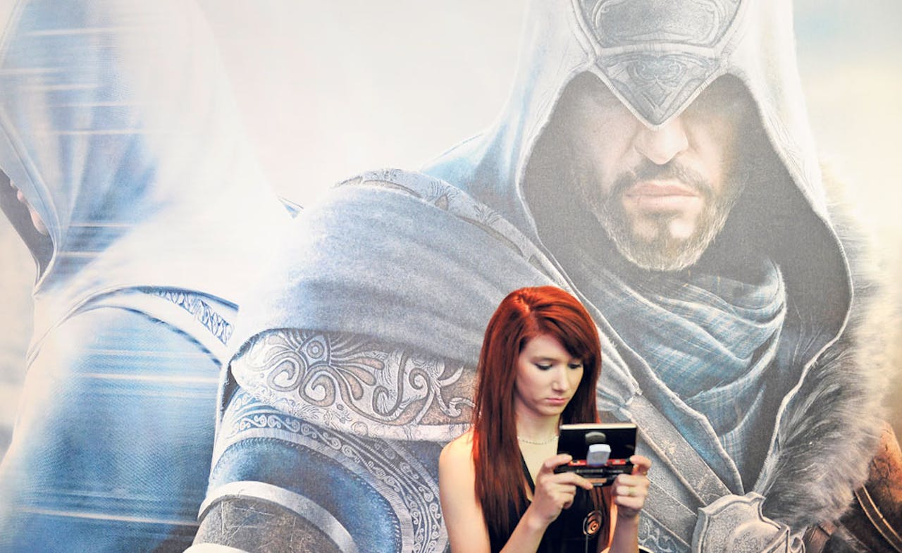 Bezoeker van de entertainmentbeurs E3 in Los Angeles speelt op een mobiel apparaat. Games zijn steeds vaker gratis te krijgen op smartphones en tablets.