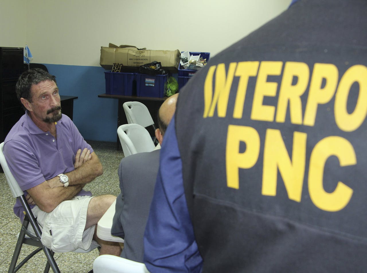 John McAfee met een agent van Interpol, na zijn arrestatie vannacht in Guatamala.