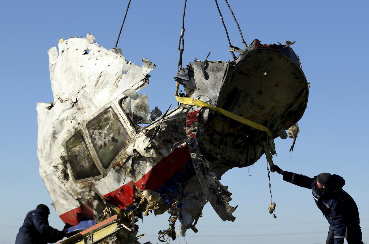 Lokale hulpdiensten laden een wrakstuk van de vlucht MH17 op een vrachtwagen.