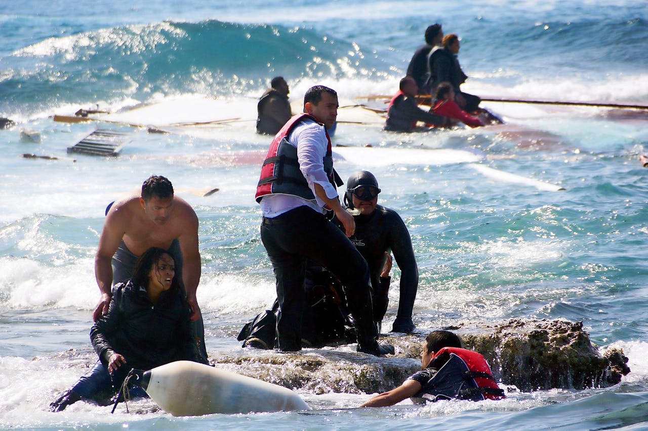 Reddingswerkers helpen bootvluchtelingen uit het water bij het Griekse eiland Rhodos. Maandag strandde daar een boot met tientallen mensen aan boord. Drie mensen kwamen om.