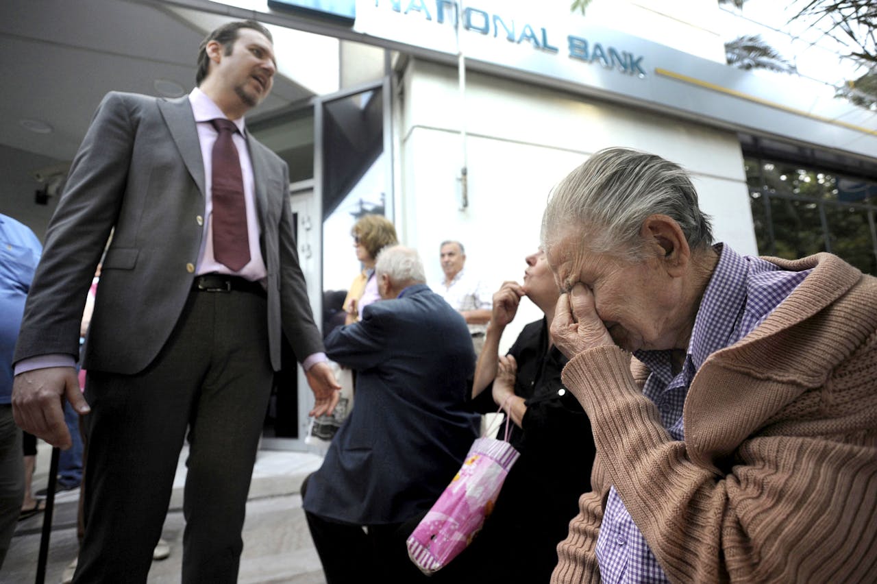 Een bankmanager legt de situatie van zijn bank uit aan ouderen die vrezen voor hun pensioen.