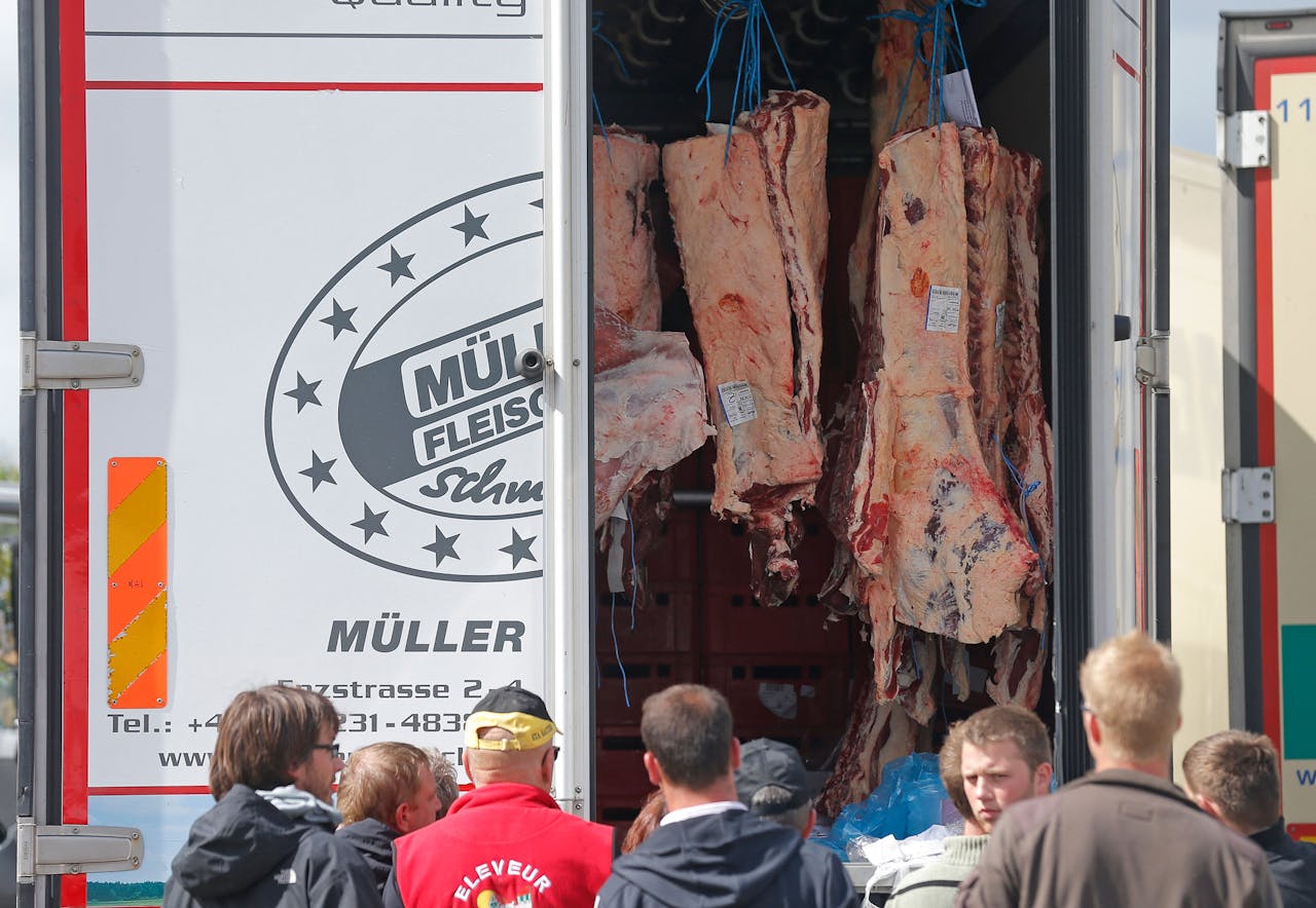 Boze Franse boeren bekijken maandagochtend bij Straatsburg de lading van een vrachtwagen van een Duitse vleestransporteur.