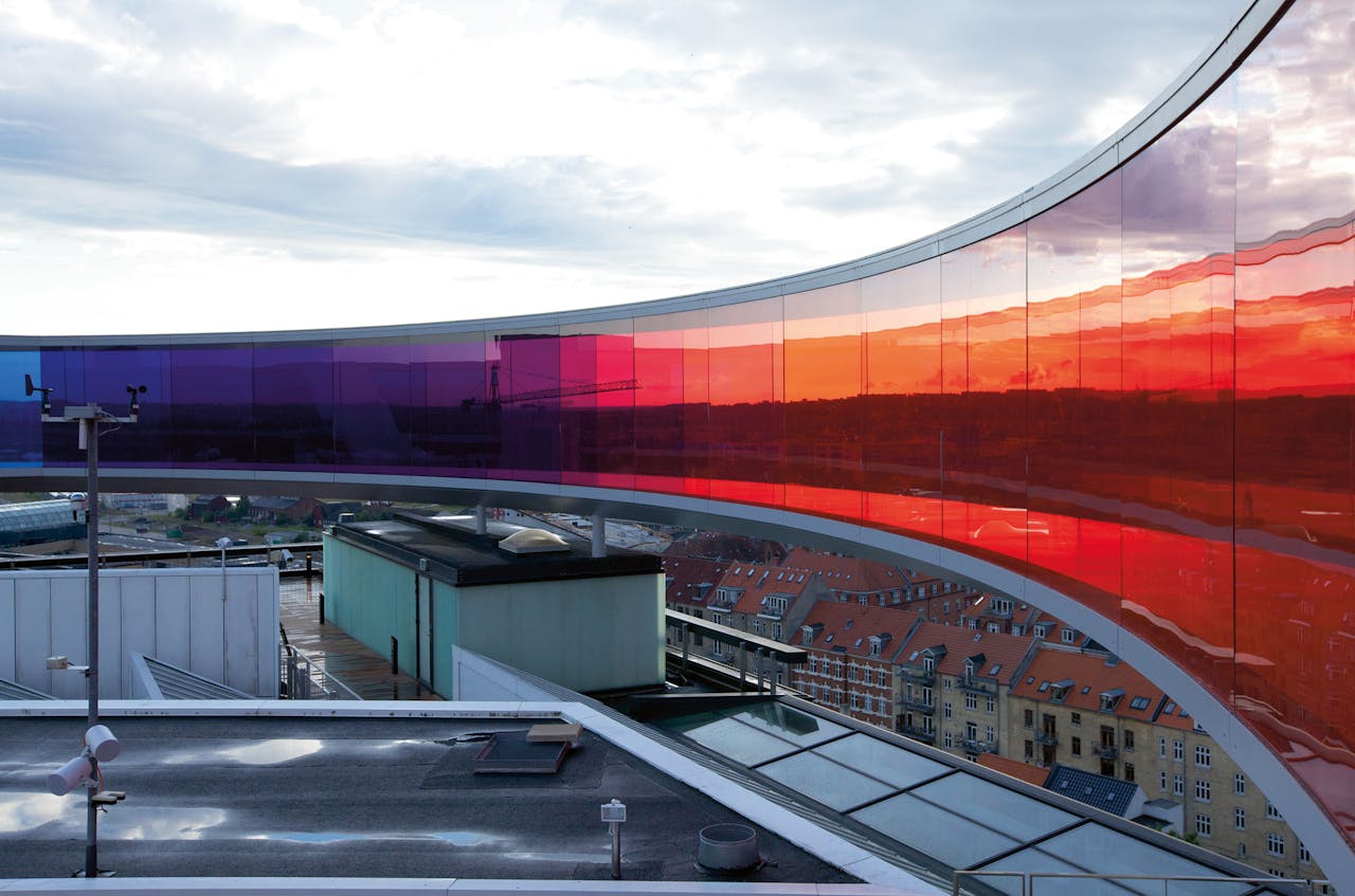 In ‘Your Rainbow Panorama’ (2011), op het dak van het ARoS-museum in Aarhus, krijgt de bezoeker steeds een andere, gekleurde blik op de stad.