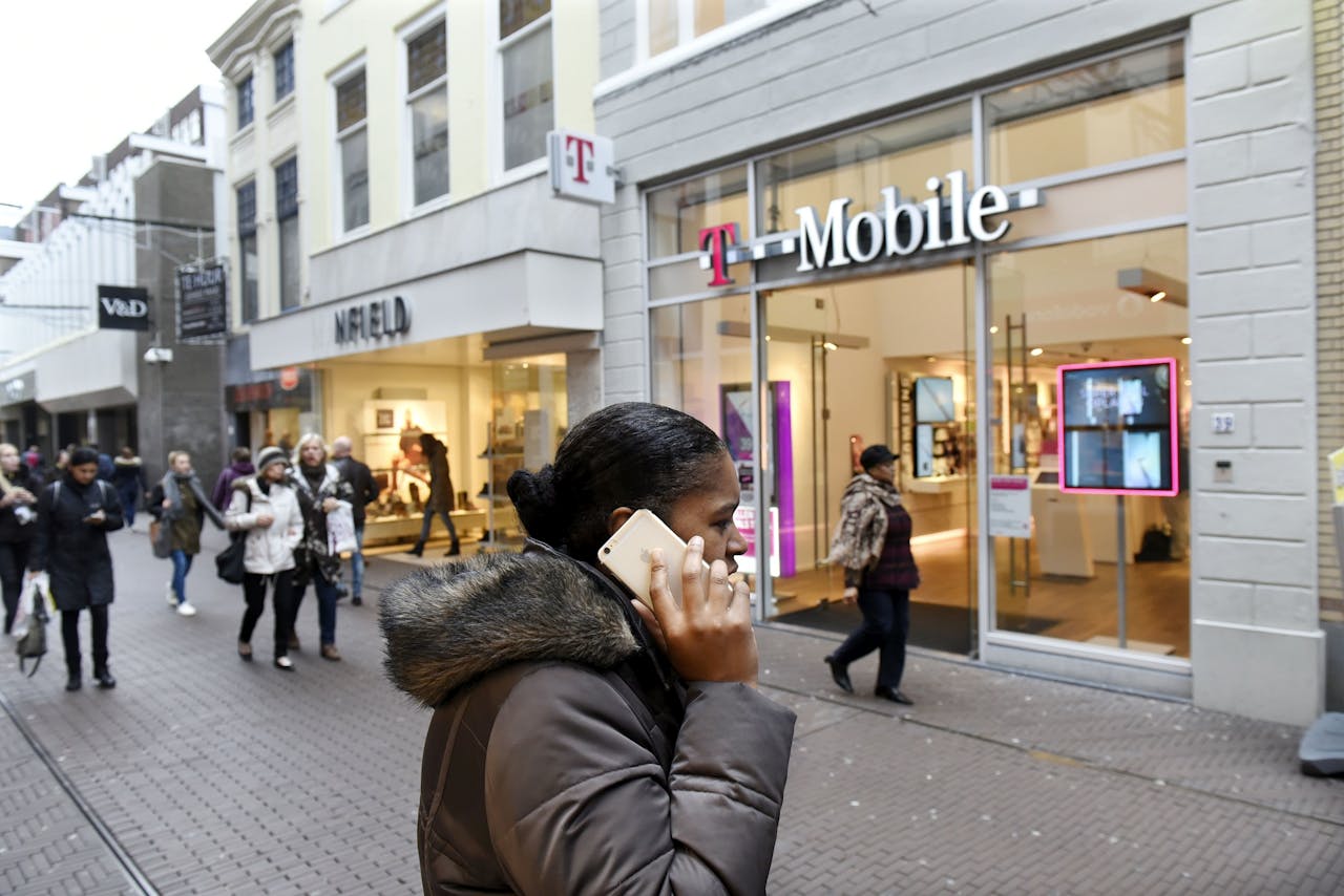 Een vrouw met telefoon voor een winkel van T-mobile in Den Haag. ConsumentenClaim spant een rechtszaak aan tegen het telecombedrijf en Vodafone. foto: HH
