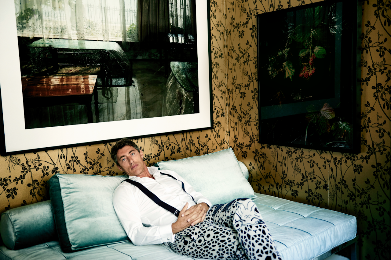 Van Vliet in een broek gemaakt van de gebreide wollen Tattoo-meubelstof die hij heeft ontwikkeld met Febrik. Het behang is van Eijffinger. Daybed Yuji, een ontwerp van Van Vliet, is gestoffeerd in een glansvelours Dandy van Christiaan Fischbacher. De grote foto boven zijn hoofd is van Sylvie Zijlmans.