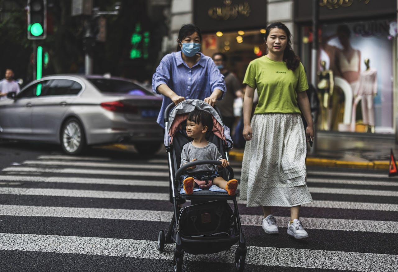 Drie Chinezen steken een zebrapad over in Shanghai. Sinds 2015 geldt in het land een zogeheten tweekindpolitiek.