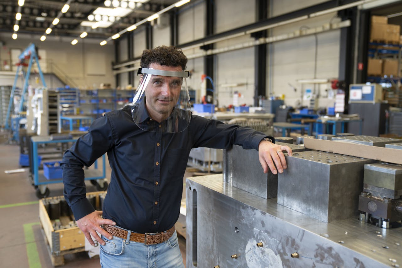 Luc van Neer, ceo van Fast Automotive Group, uit Geleen demonstreert in de fabriekshal van prototypebouwer Kupron in Sittard de eerste 'face protection shield'.