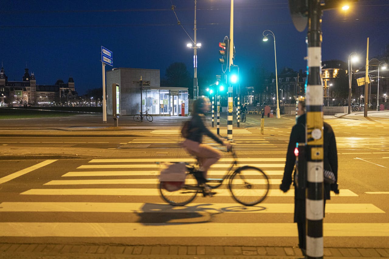 Een fietser fietst vlak voor het ingaan van de avondklok door rood licht op het Amsterdamse Museumplein.