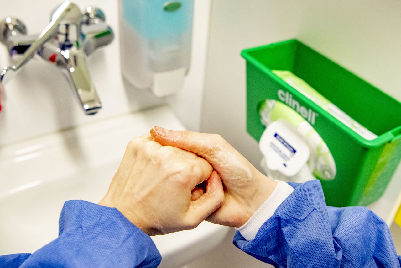Handen wassen bij voorbereiding van de quarantaine kamer voor corona patiënten in een ziekenhuis. Goed je handen wassen en afwachten hoe het virus zich ontwikkelt is echter geen optie in Den Haag, realiseerde de coalitie zich maandag.