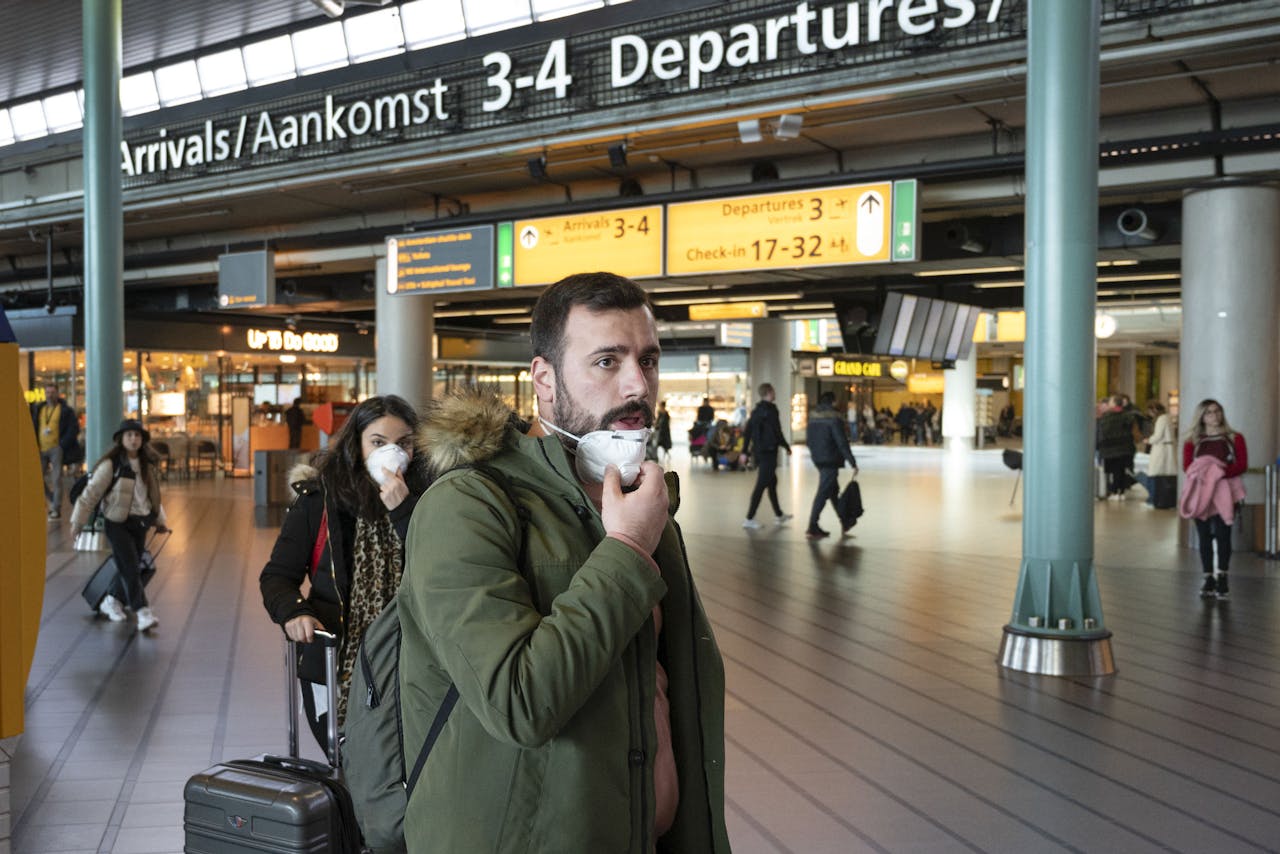 Reizigers woensdagmiddag op de luchthaven Schiphol. Bij telecombedrijf KPN geldt sinds dinsdag een verbod op alle buitenlandse reizen.